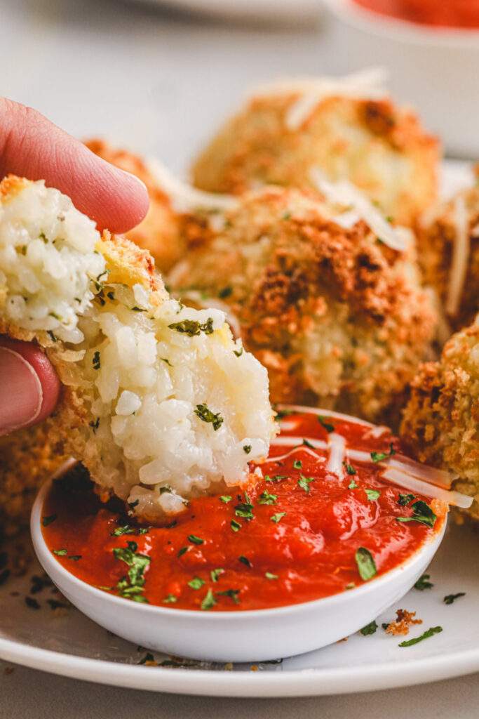 Air Fryer Arancini Rice Balls being dipped into red sauce