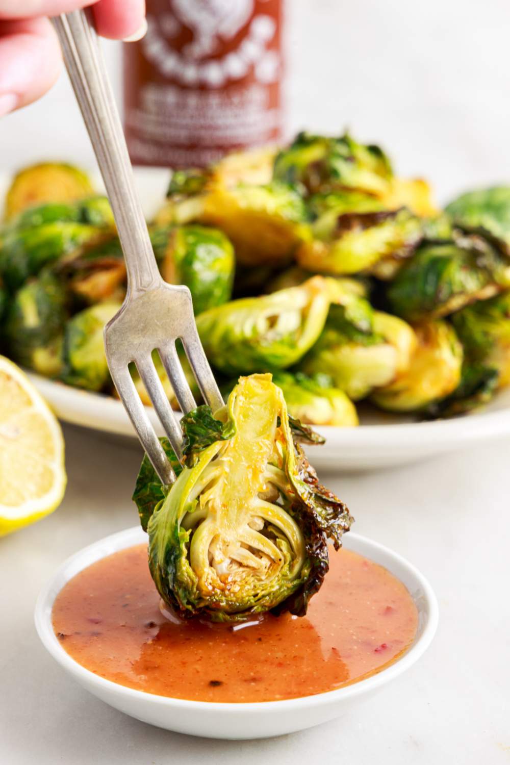 dipping a sprout in sauce with a fork