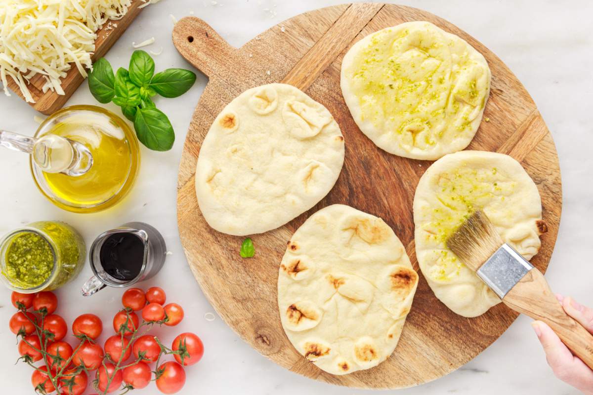 brushing pesto mixture onto naan bread