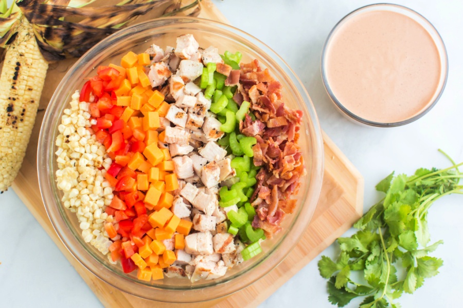 ingredients for bbq chicken pasta salad in a mixing bowl