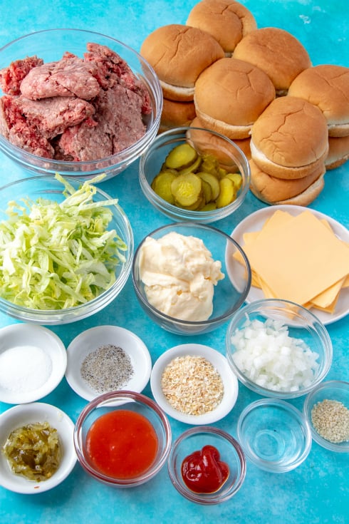 Big Mac Sliders - Ingredients for recipe in small bowls- shredded lettuce, dressing, mayo, seasonings, onion, relish, cheese slices, beef and buns