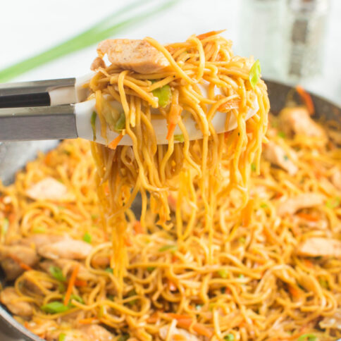 Chicken Chow Mein in a pan with tongs pick up some