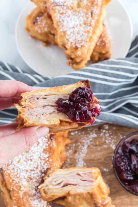 hand holding a monte cristo sandwich dipped in jam