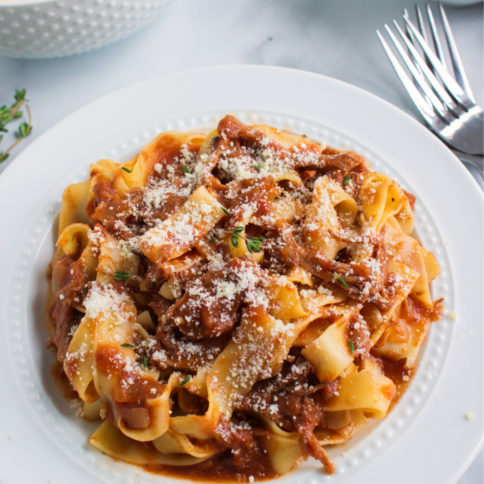 ragu served with noodles on a white plate