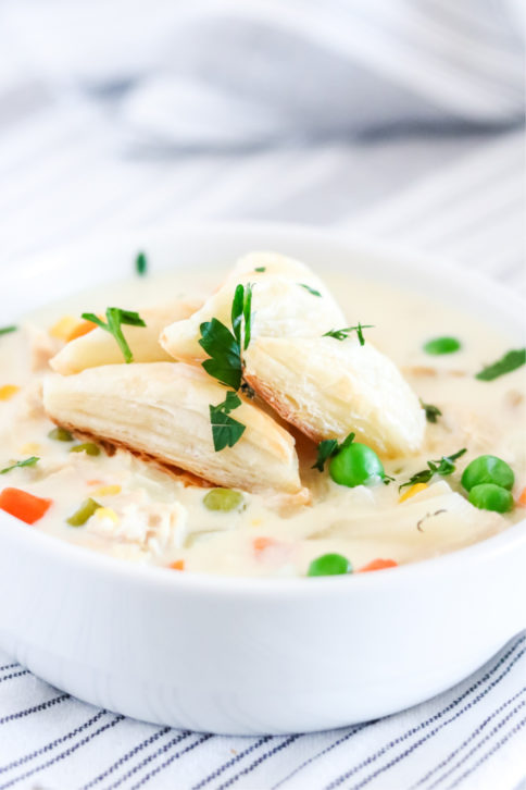 Crockpot Chicken Pot Pie Soup in a white bowl - with puff pasty triangles on top