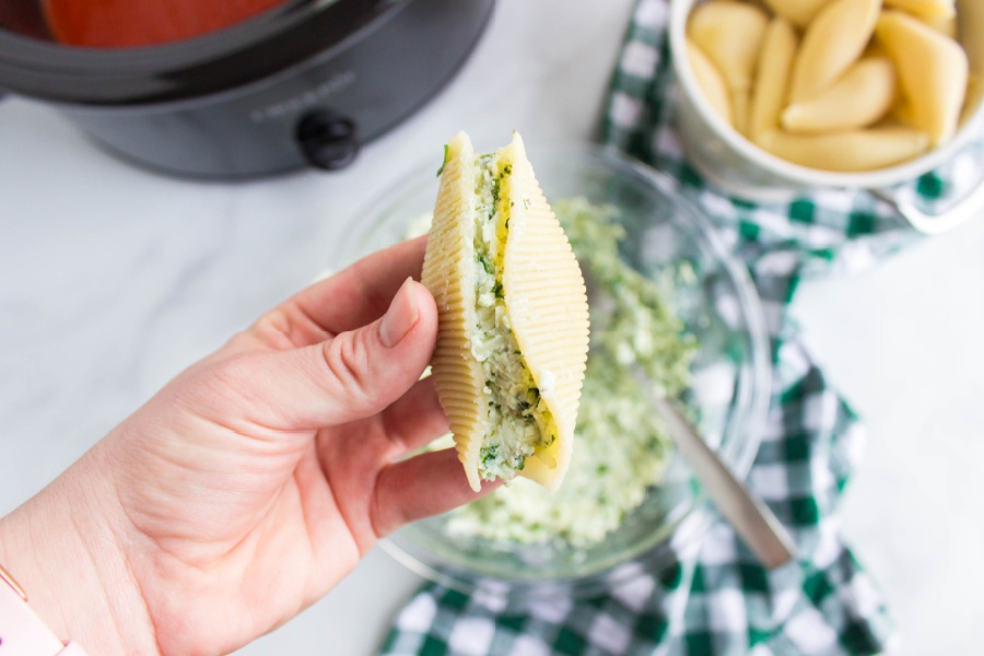 hand holding a shell stuffed with cheese mixture