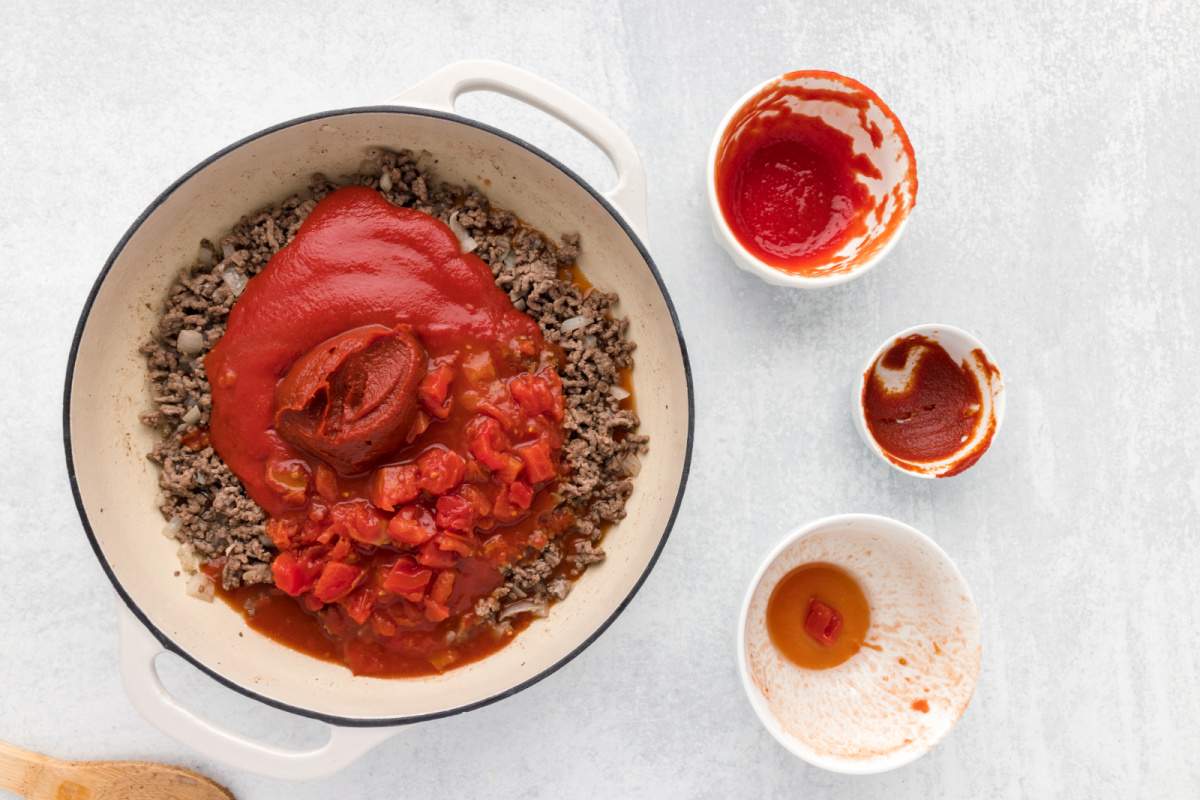 Adding the tomato sauce, tomato paste, and diced tomatoes to the skillet