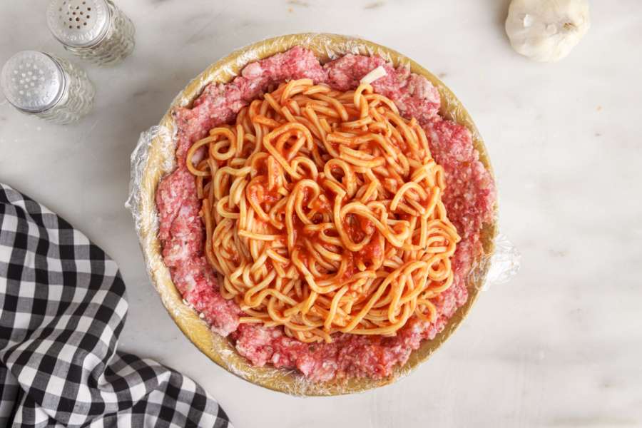 adding pasta into meat bowl