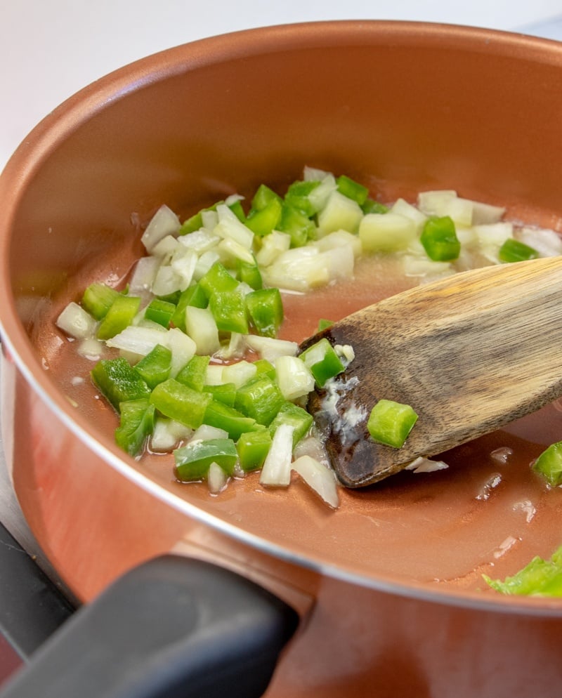 onions and peppers sauting in a pan with butter