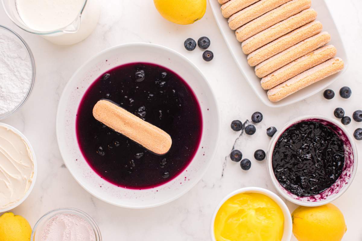 dipping  lady fingers in blue berry mixture