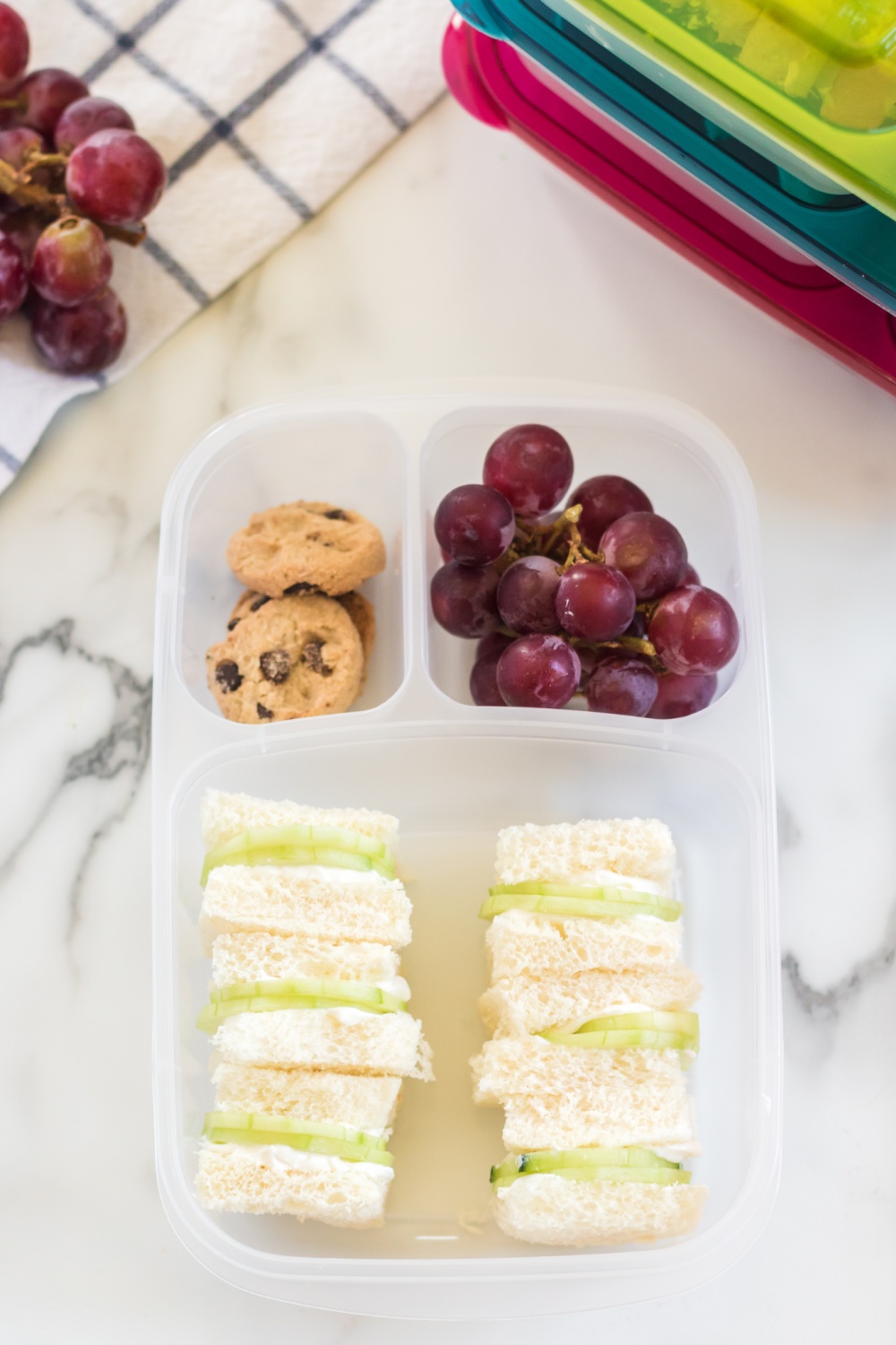 top down photo of lunchbox packed with mini cucumber sandwiches