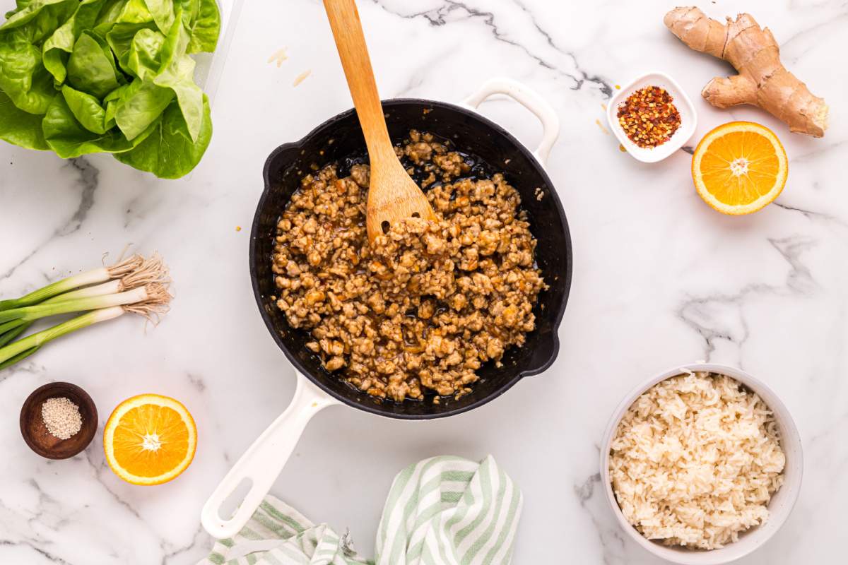 stirring orange ground chicken in pan