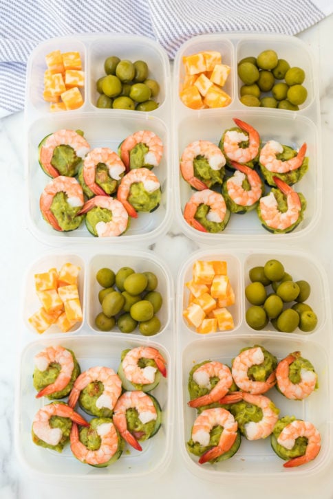 Top down photo of 4 easy lunchboxes with Shrimp Avocado, guacamole, olives and cheese cubes