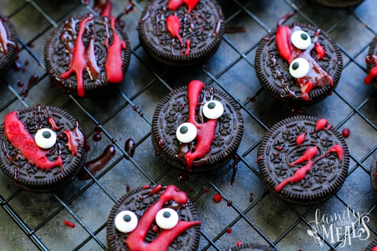 Spooky Halloween Oreos - Oreo cookies layed out on a drying rack with red frosting splattered and candy eyes