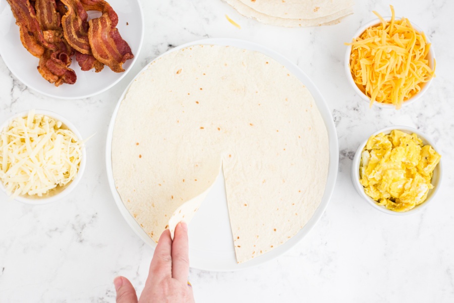 hand holding up the cut part of tortilla