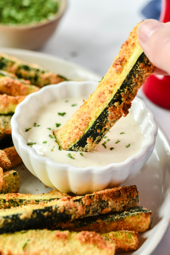 dipping a zucchini fry in sauce