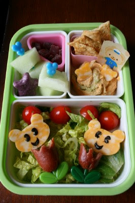 Top down picture of Bento Love : Tulips lunch box - hot dogs shaped like tulips, cheese shaped bears with nori eyes and mouth, fruit, humus and chips