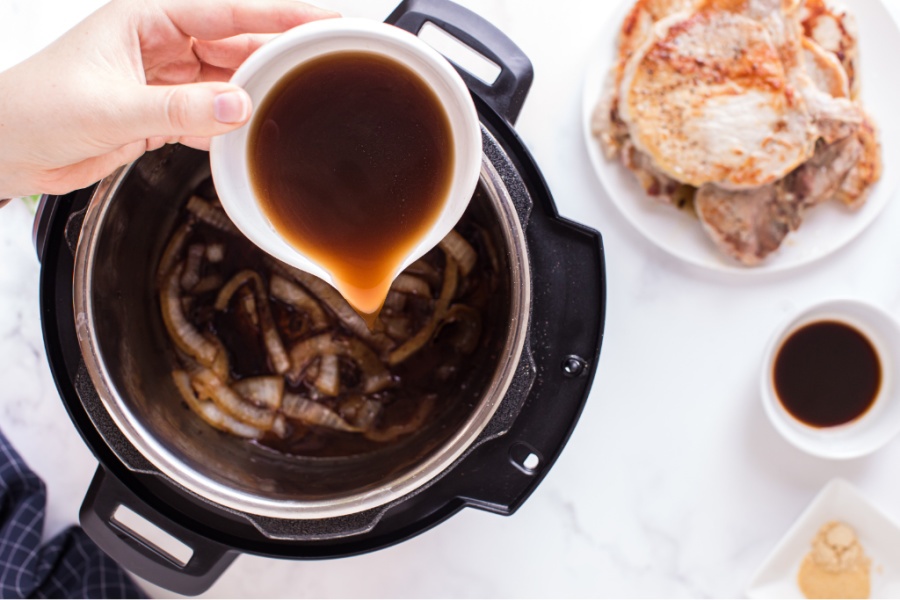 pouring broth into instant pot with onions